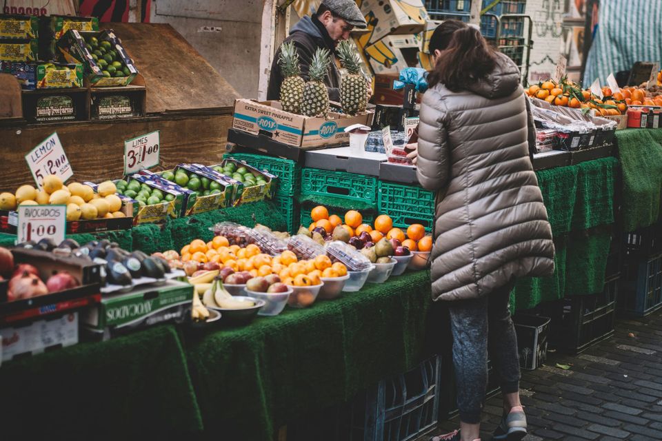 A woman buys something from a fruit vendor