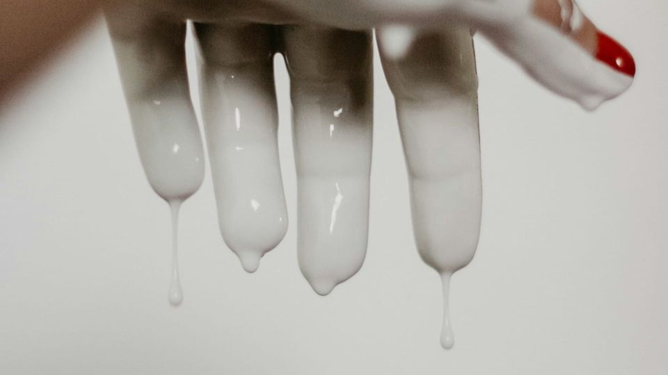 A hand is raised in front of the camera as white glue or paint drips off its fingers. AWS Glue service will now feature two powerful workers in six new regions