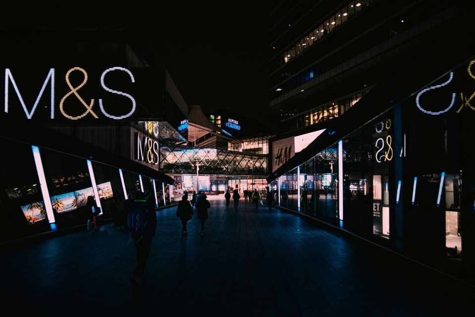 An M&S store at night as customers walk through a shopping centre. The retailer suffered a major cyber attack in April