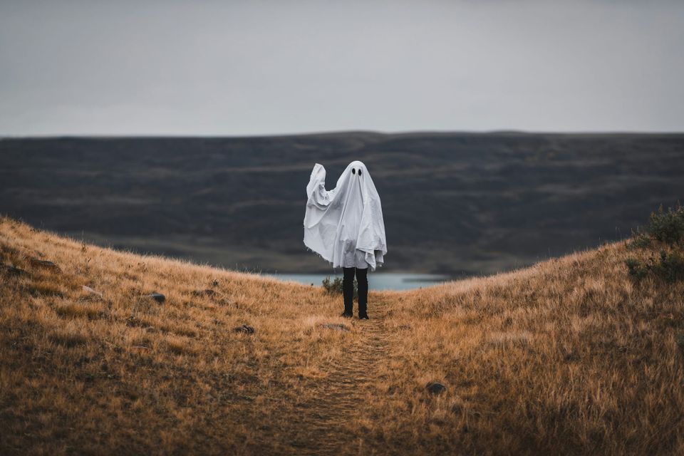 A person wearing a white sheet, dressed like a ghost, waves at the camera. Researchers said a flaw with a windows scripting engine saw the ghost of internet explorer haunt users
