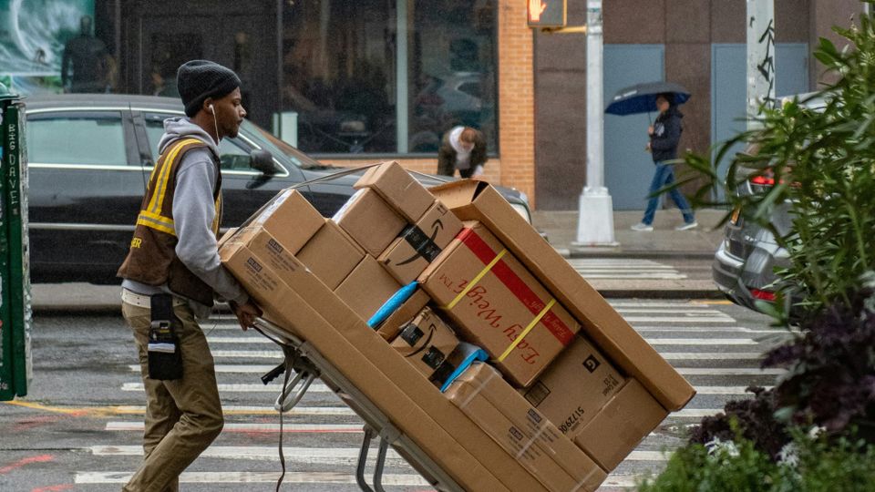 A delivery person pushing packages along the street. The UK tech industry says the success of the government's industrial strategy will depend on its deliver