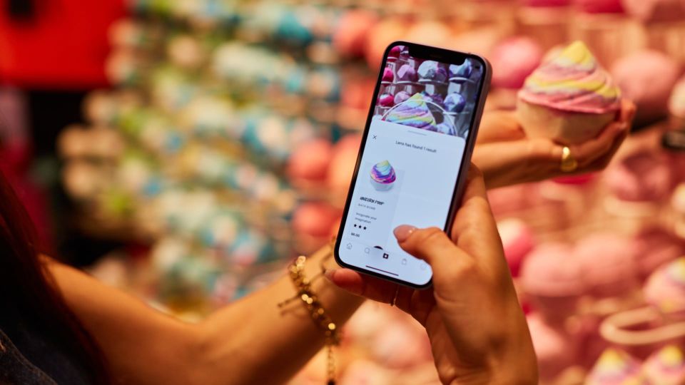 A person holds up a phone in front of a bath bomb, using an app to identify the Lush product. The Lush Lens feature uses Google's Gemini AI tools.