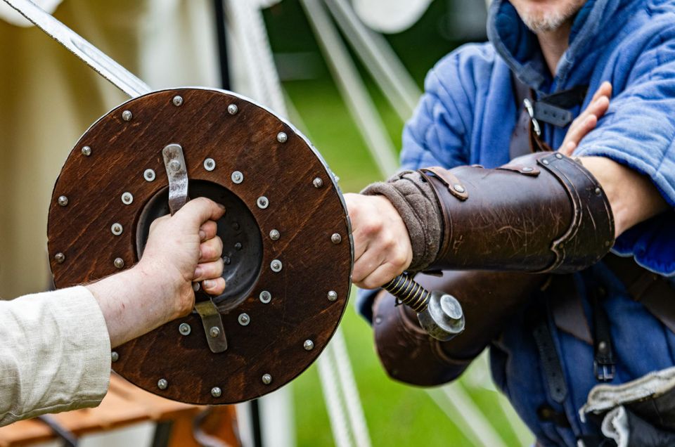 A person uses an old viking shield to block someone with a sword. Google's OSS Rebuild platform uses AI to enhance open source security