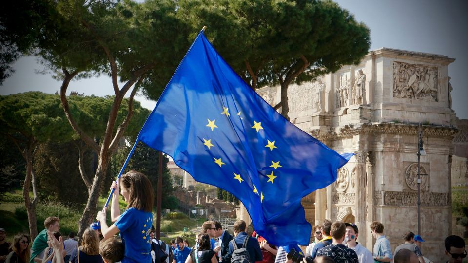 A woman holds an EU flag up among a crowd.