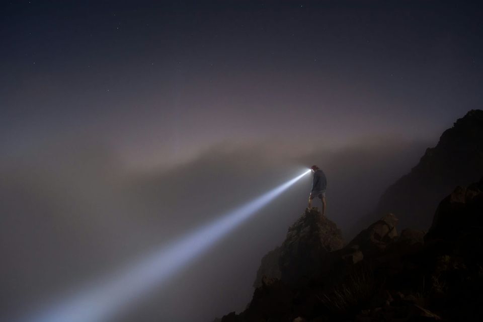 A man stands on a rocky outcrop at night with a headtorch shining into fog. AI ransomware model PromptLock was discovered by ESET.