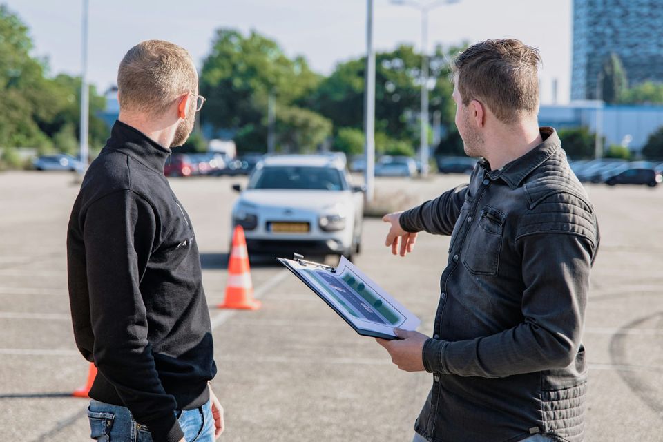 A driving instructor teaching a student while stood in front of a car. The UK DVSA is spending £73 million on a new test booking system