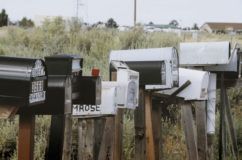 A group of mail boxes on posts by the side of the road.