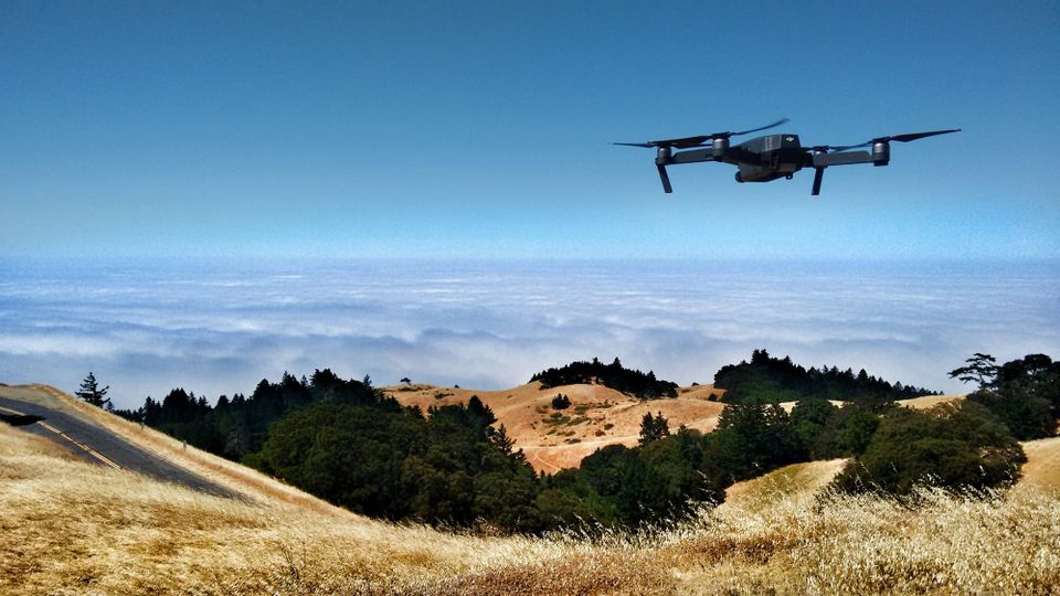 A drone flying over hills with clouds in the distance. StirlingX is a drone startup
