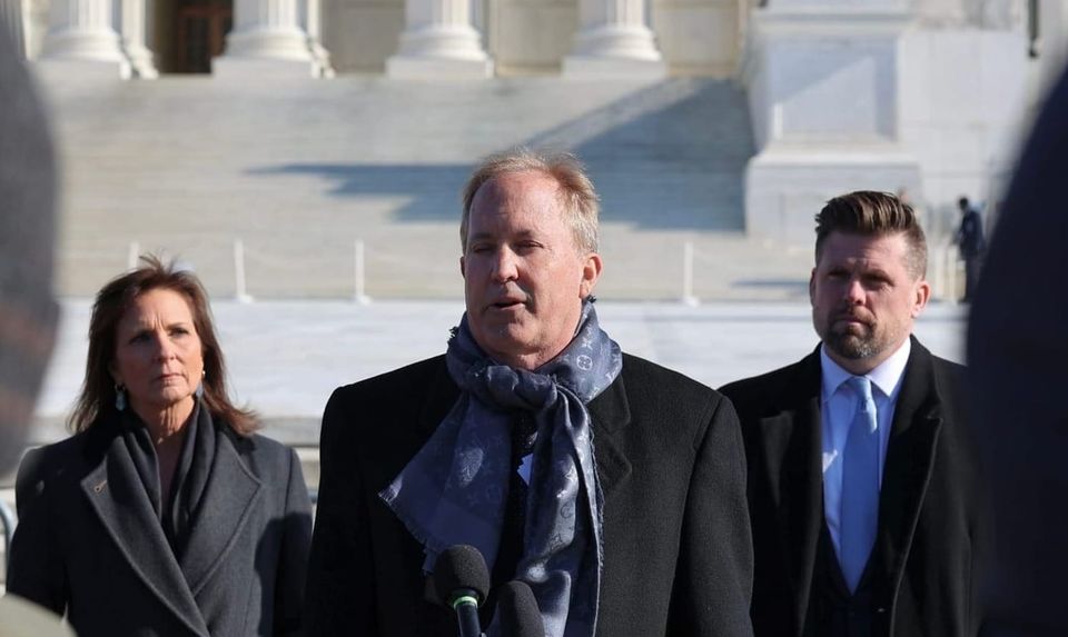 Texas Attorney General Ken Paxton holding a press conference outside a court building.