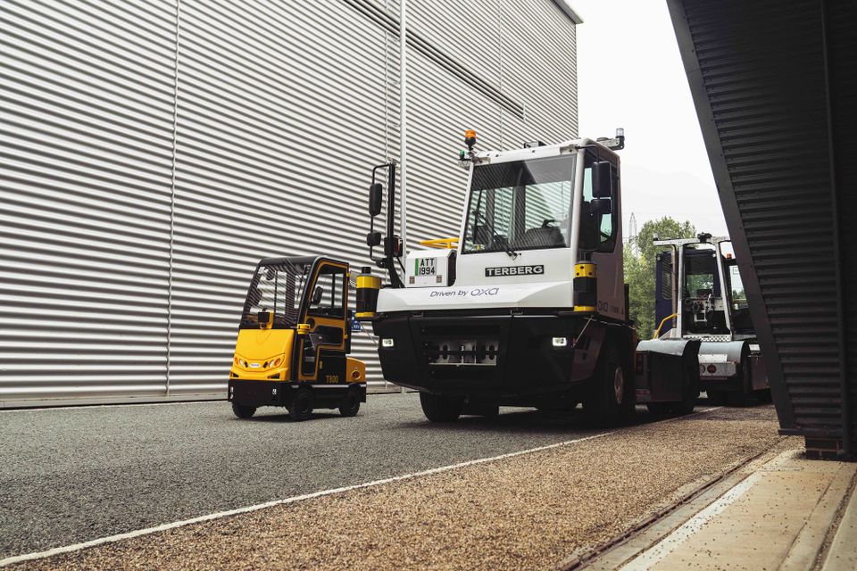 Two autonomous vehicles sit outside a warehouse