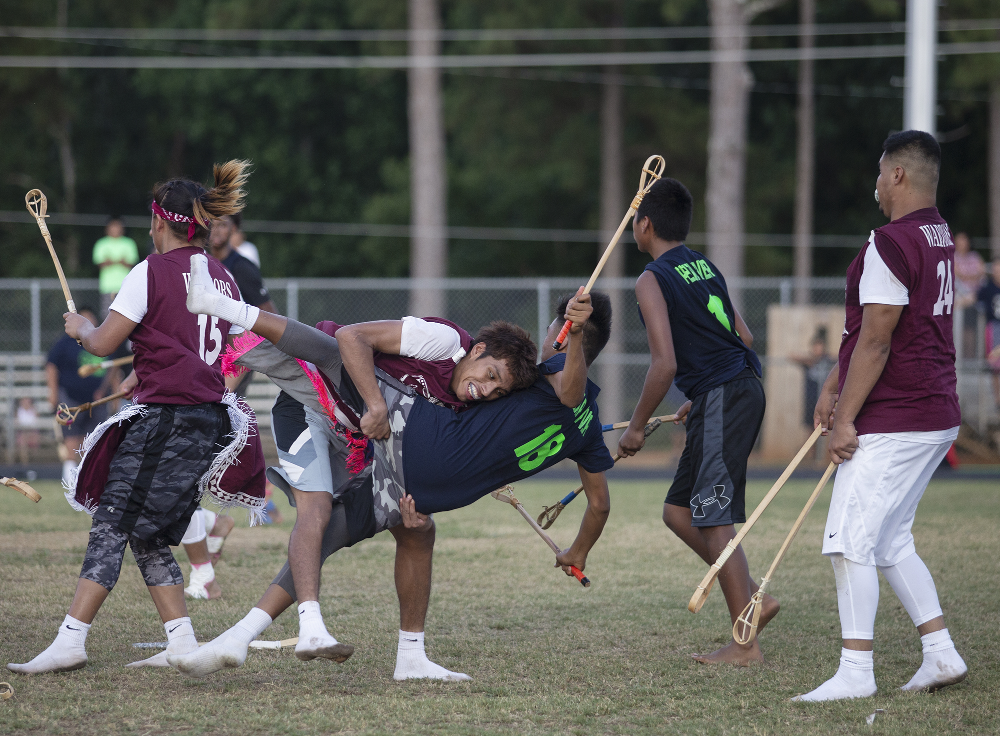 Stickball players on a field, one player tackling another
