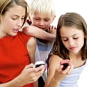 Young Girls Operating Cell Phones with a Young Boy (10-14) Standing Behind Them