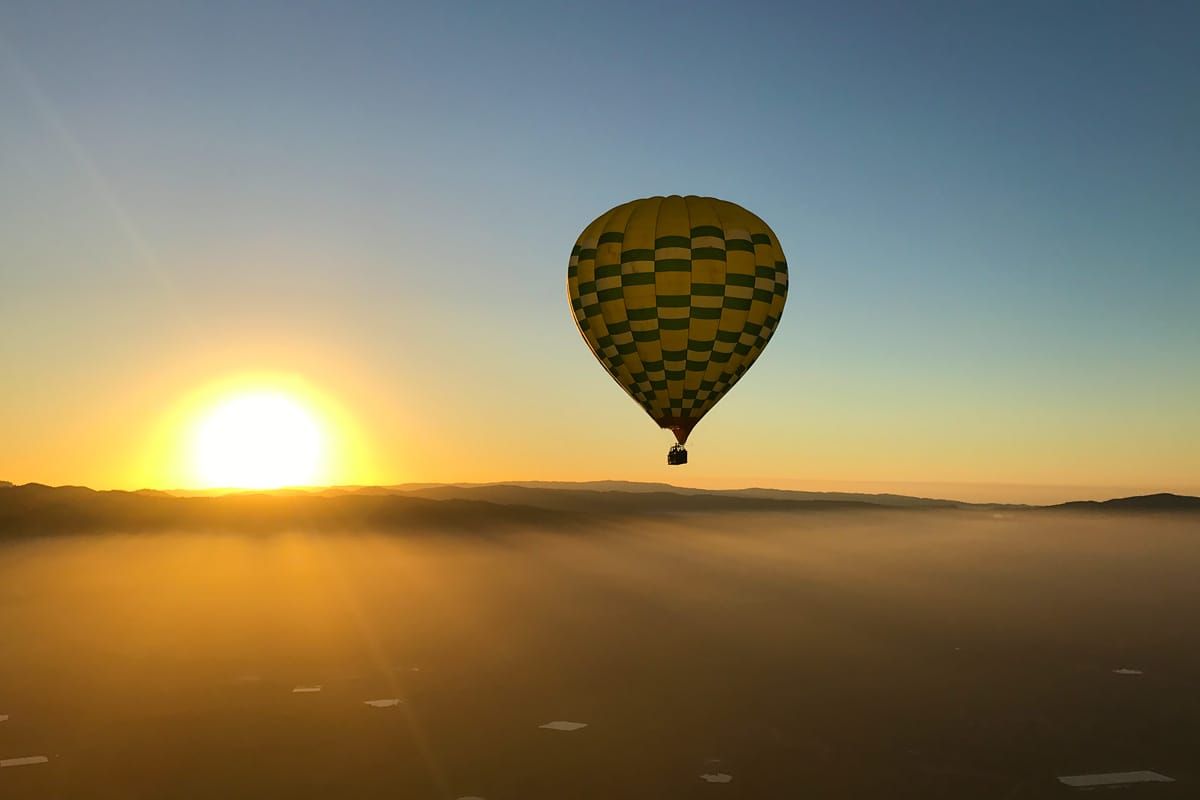 Hot air balloon ride over Napa Valley California at sunrise with clouds
