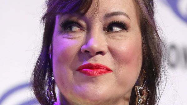 Close-up of Jennifer Tilly with red lipstick and statement earrings, exuding glam and playful charm.
