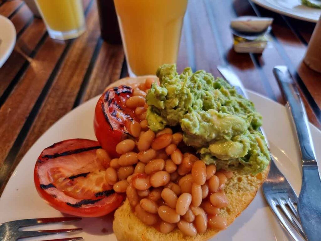 Beans, avocado and tomato vegan toast on a white plat on a wood table at the reef view hotel on hamilton island