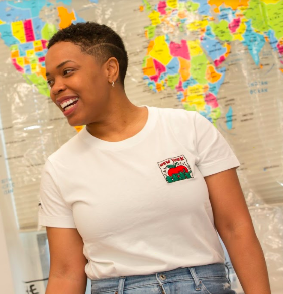 A woman standing in front of a world map and smiling. 