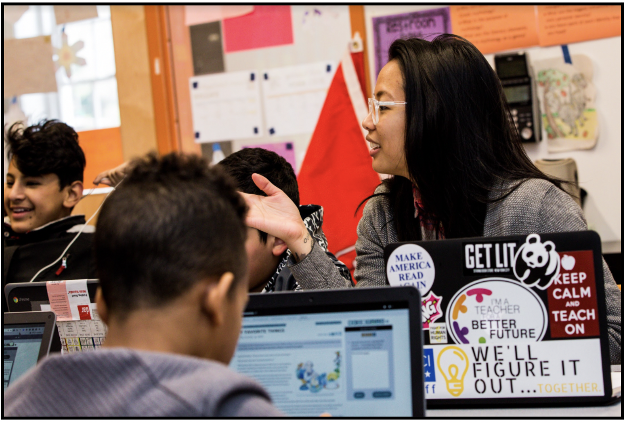 A teacher and students sitting at a table working on CommonLit lessons. 
