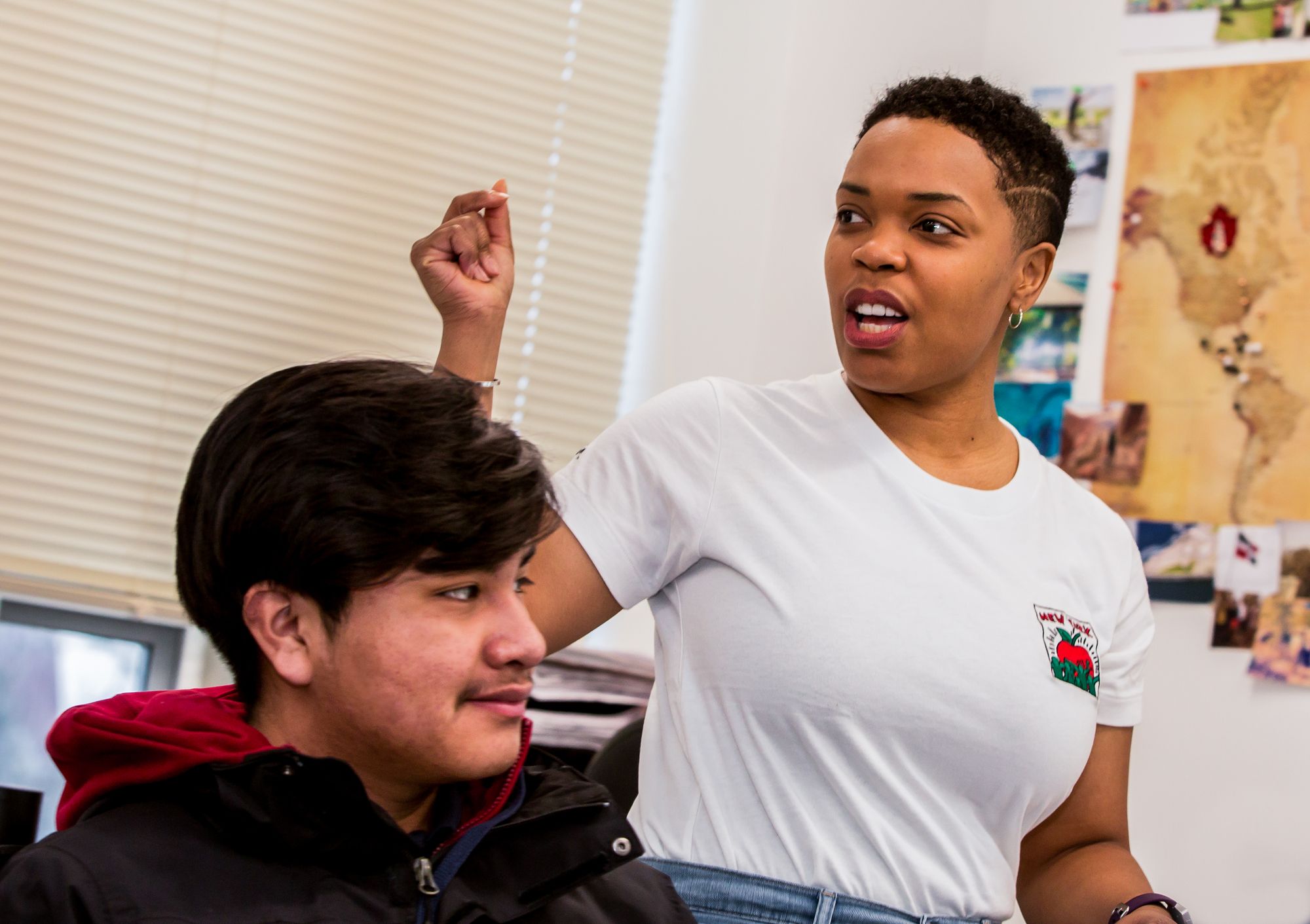 A teacher standing next to their student, lecturing.