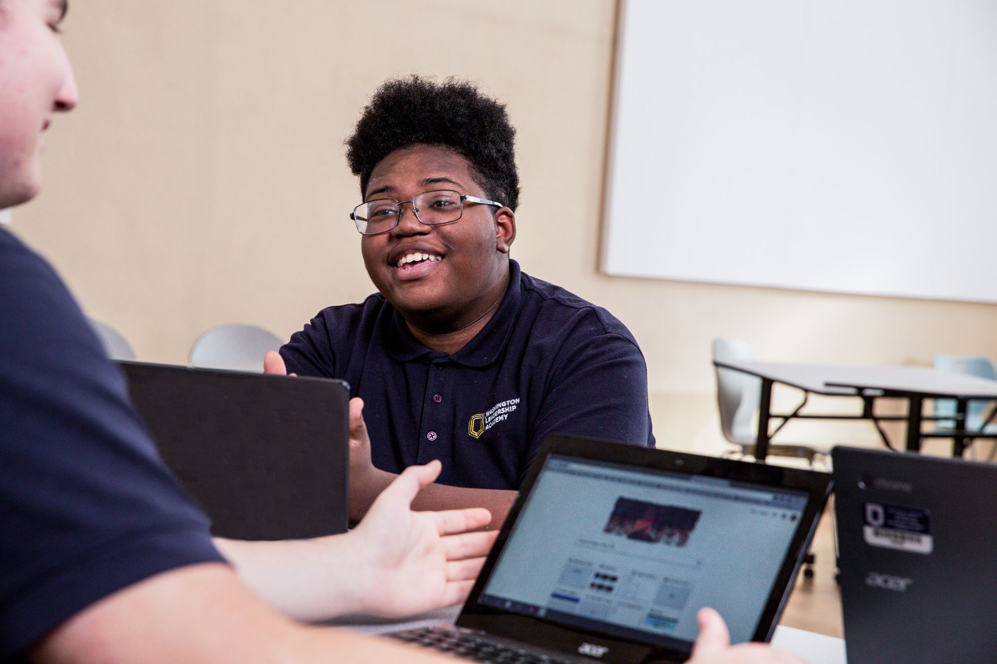 Teenage boy smiles while completing a CommonLit lesson on laptop. 