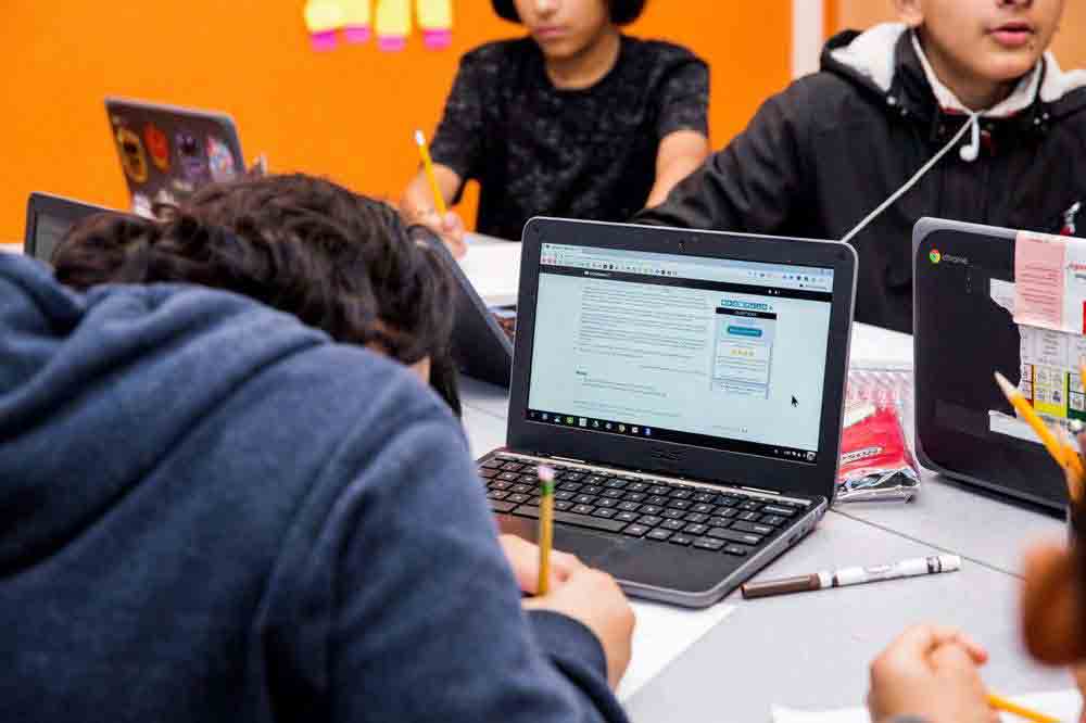 Students sitting at a table and working on CommonLit lessons. 