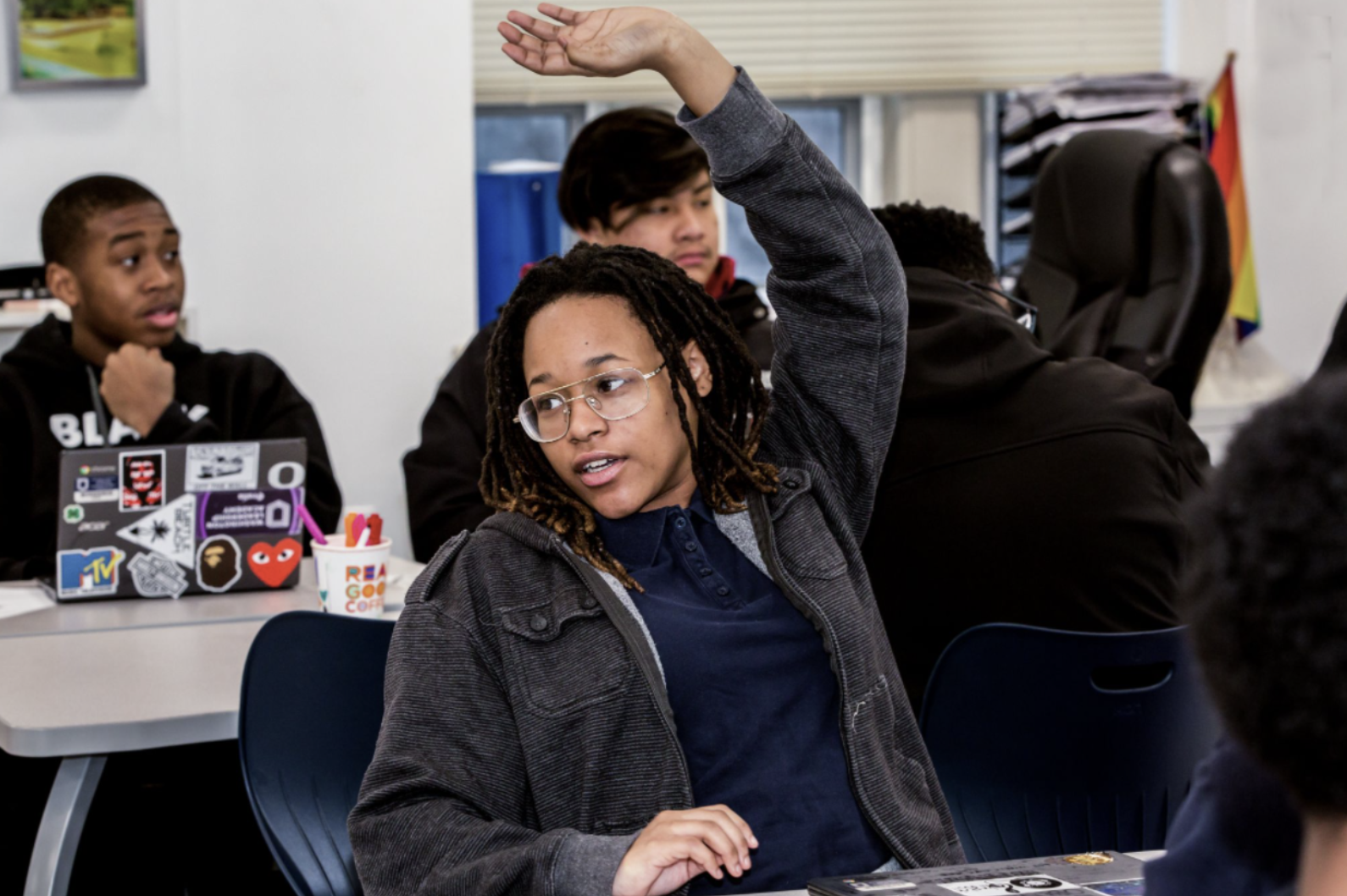 Teenage student raises hand during class. 