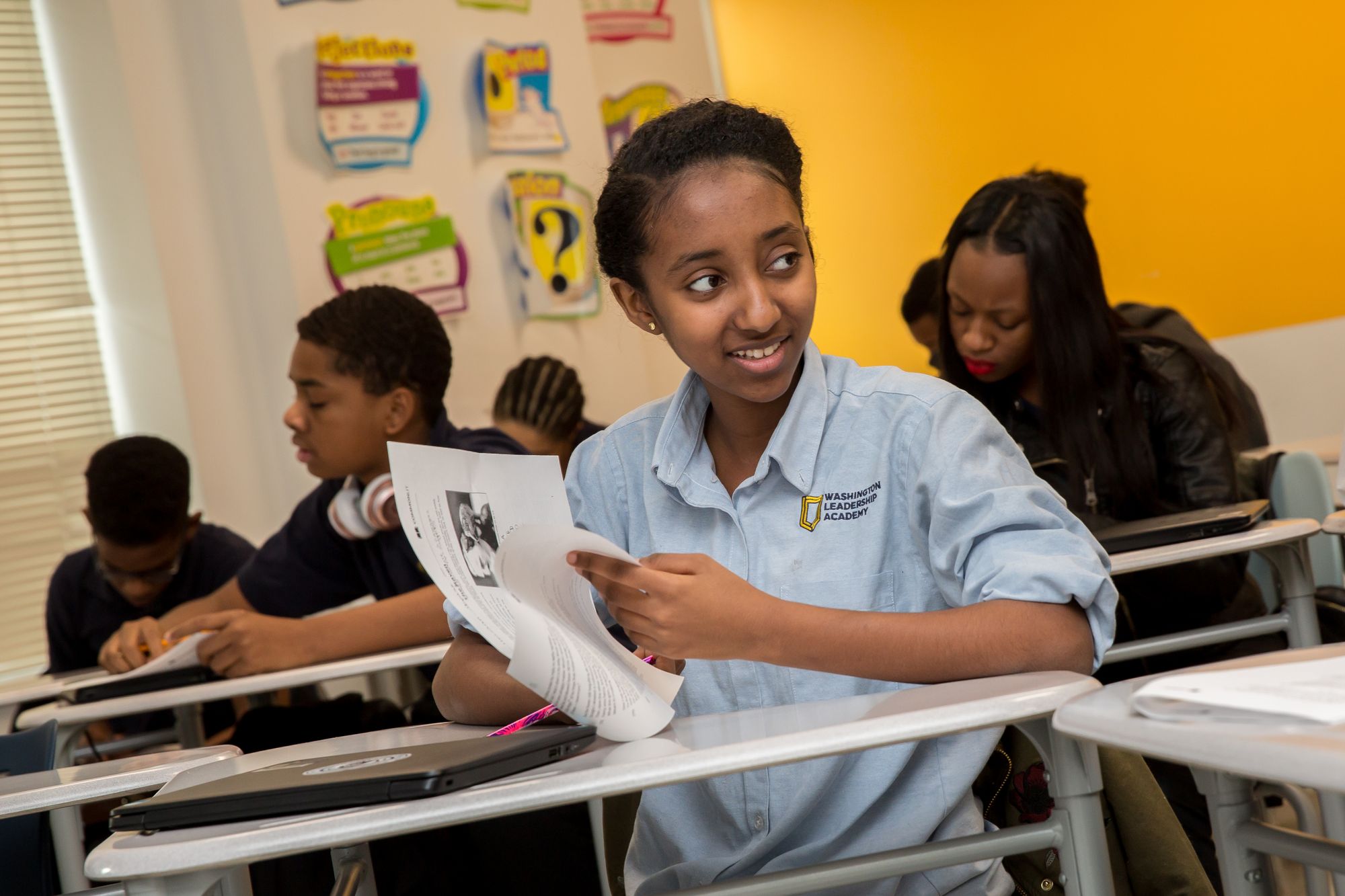 A student is smiling with a CommonLit text handout in hand.