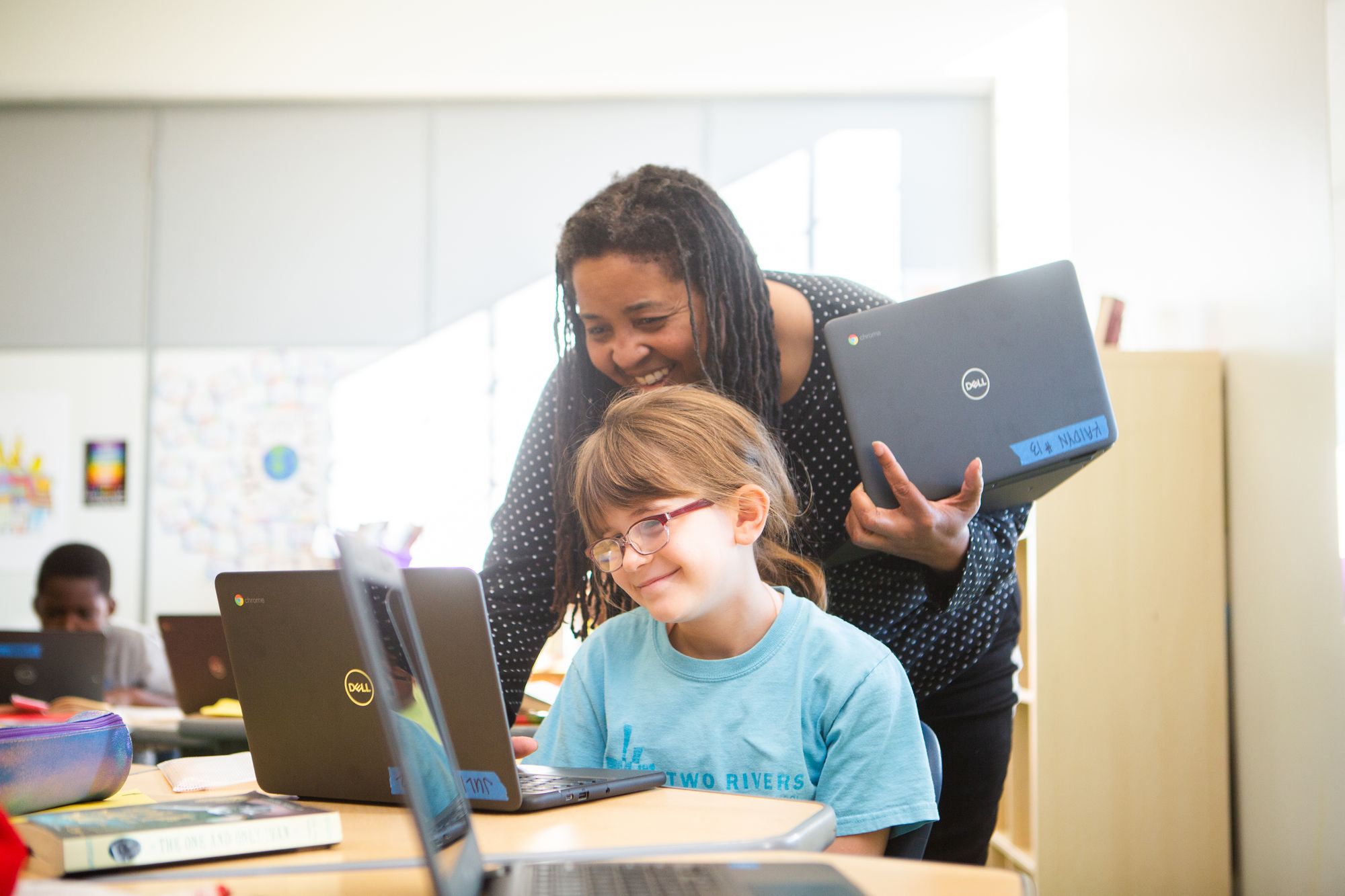 A teacher and a student smiling as they work on a CommonLit lesson. 
