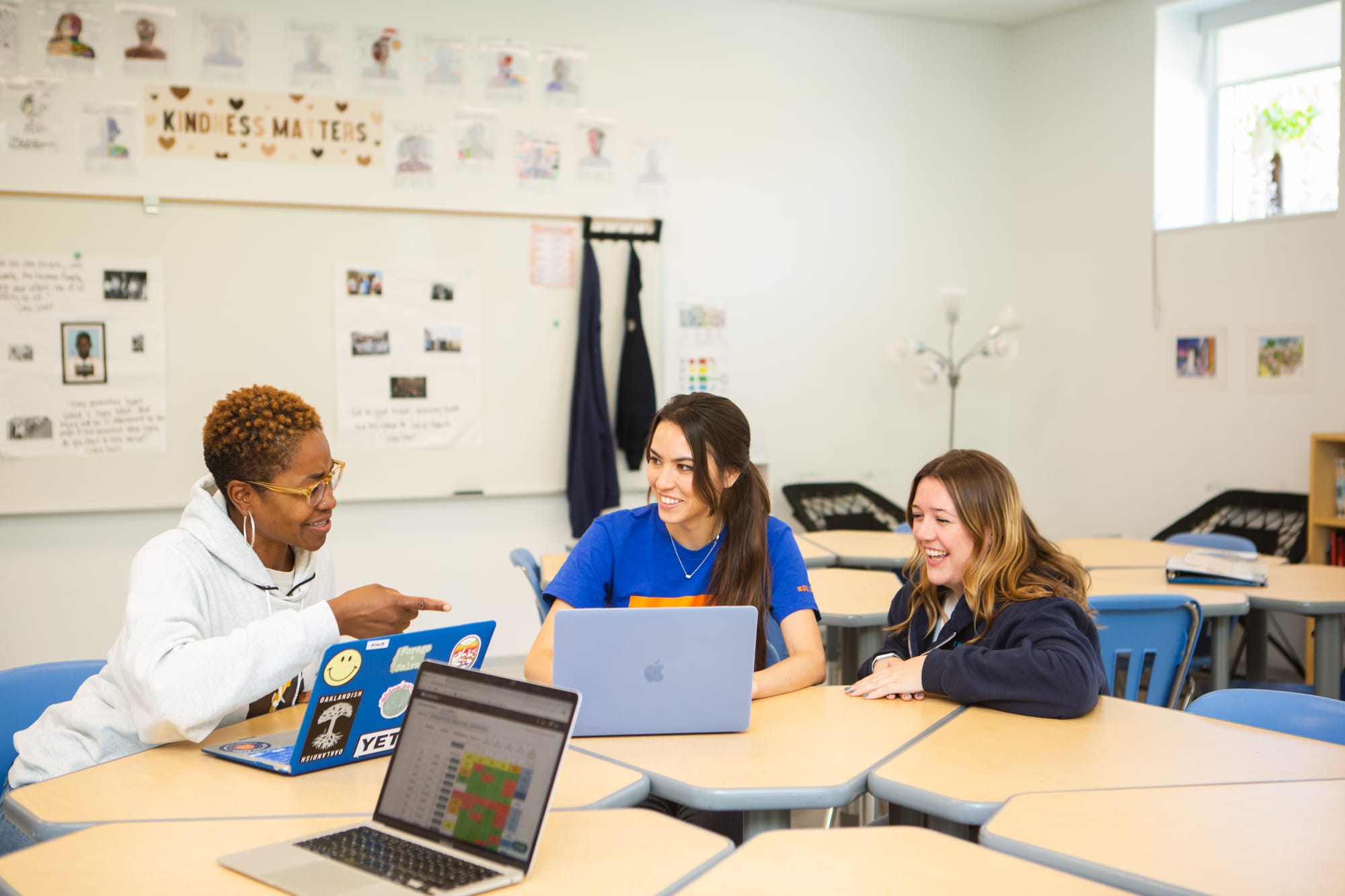 Three teachers laughing as they work on their laptops