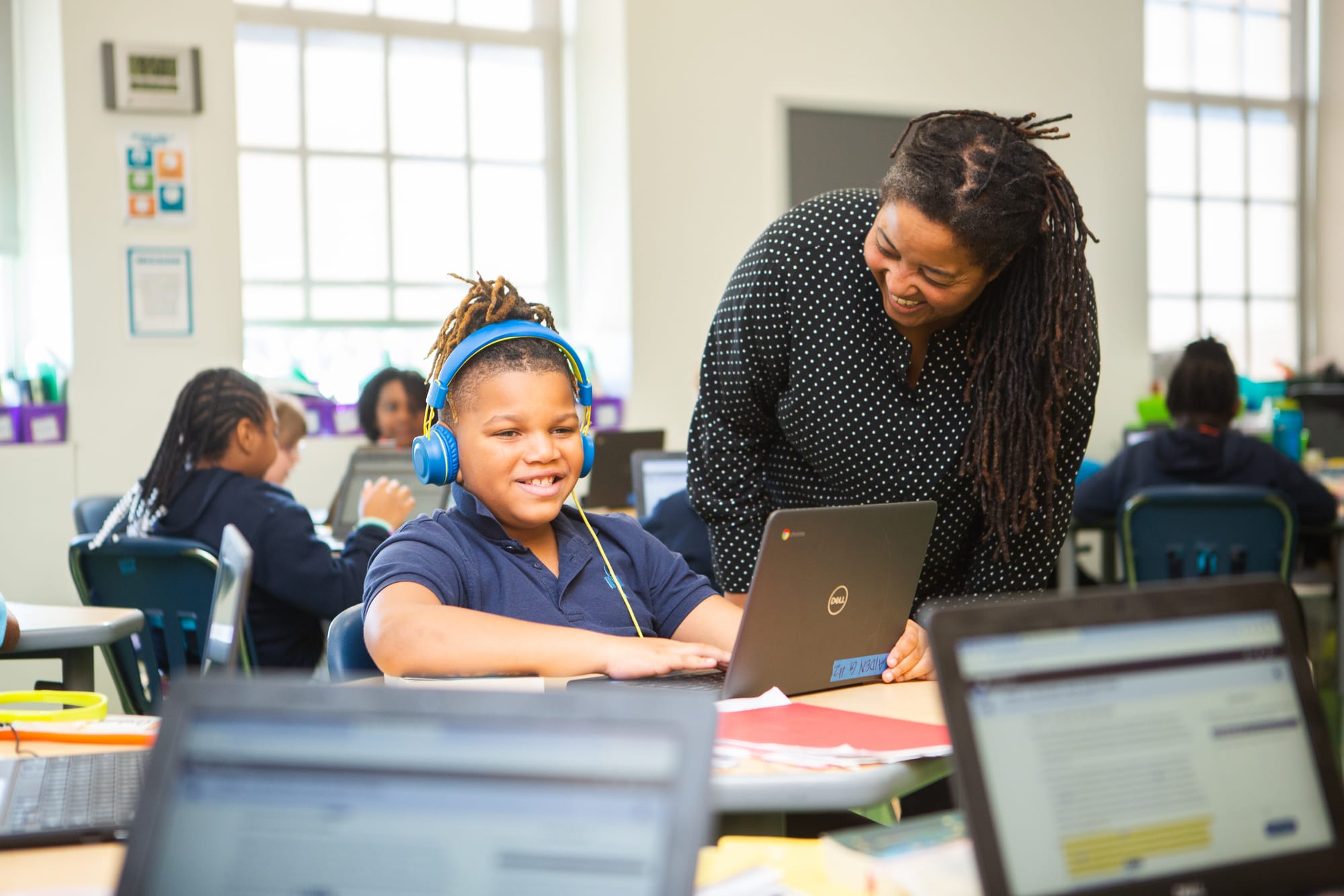 A teacher helping their student on their laptop.
