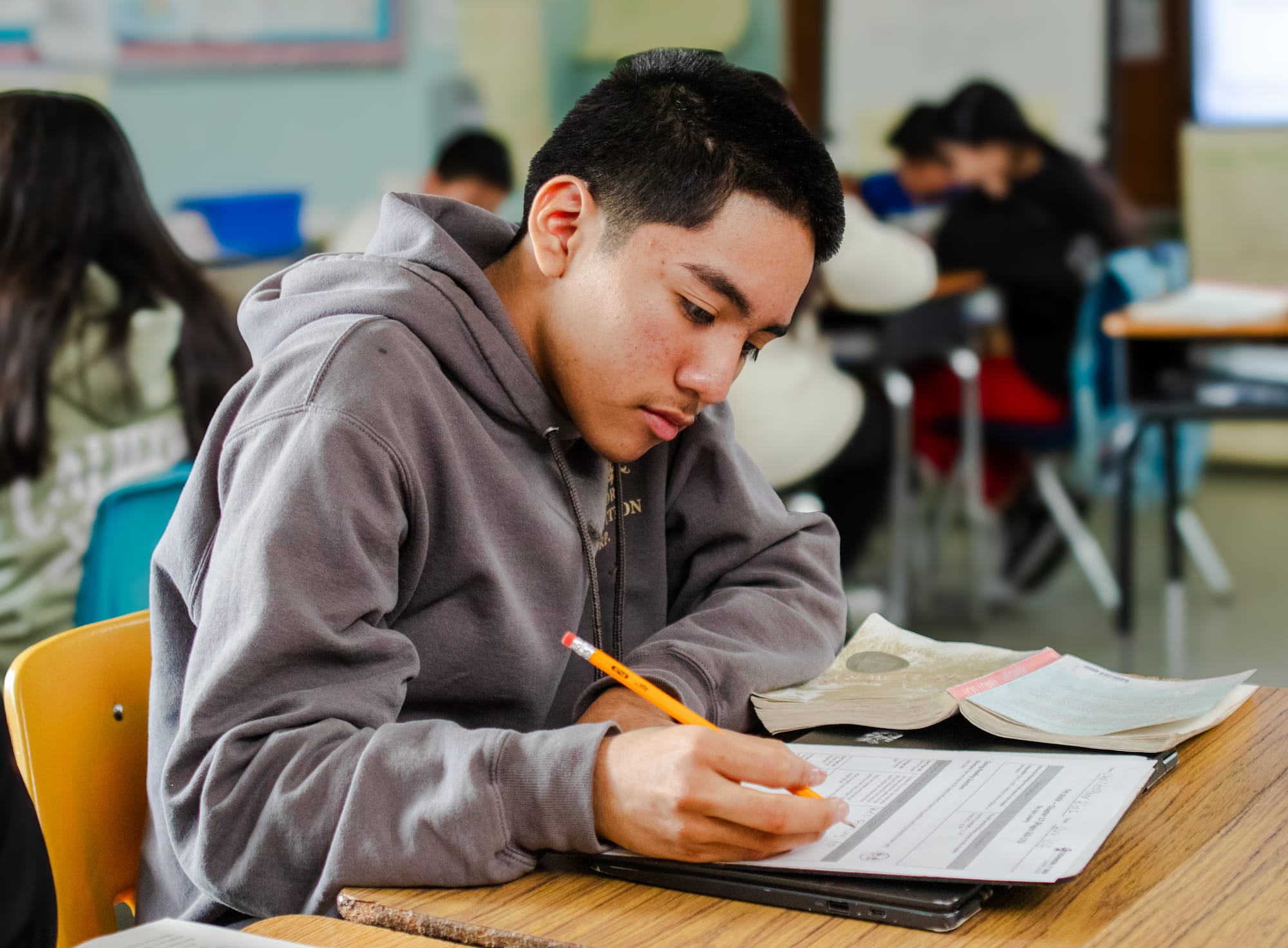 A middle school student writing at his desk.