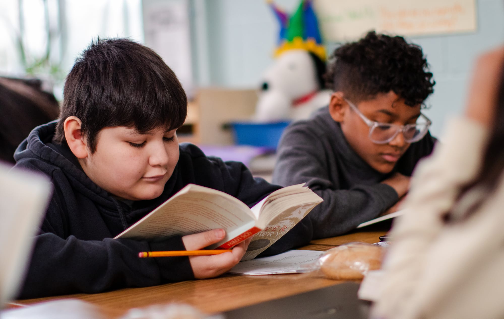 Two student read Lois Lowry's The Giver in a classroom.
