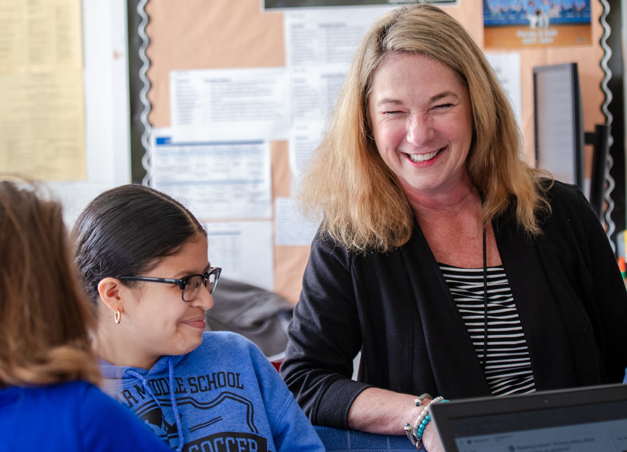 A middle school teacher smiling with her students.