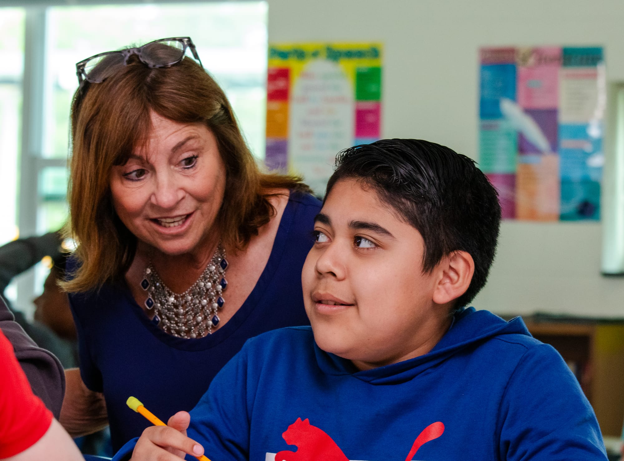 A middle school ELA teacher helping a student with an assignment.