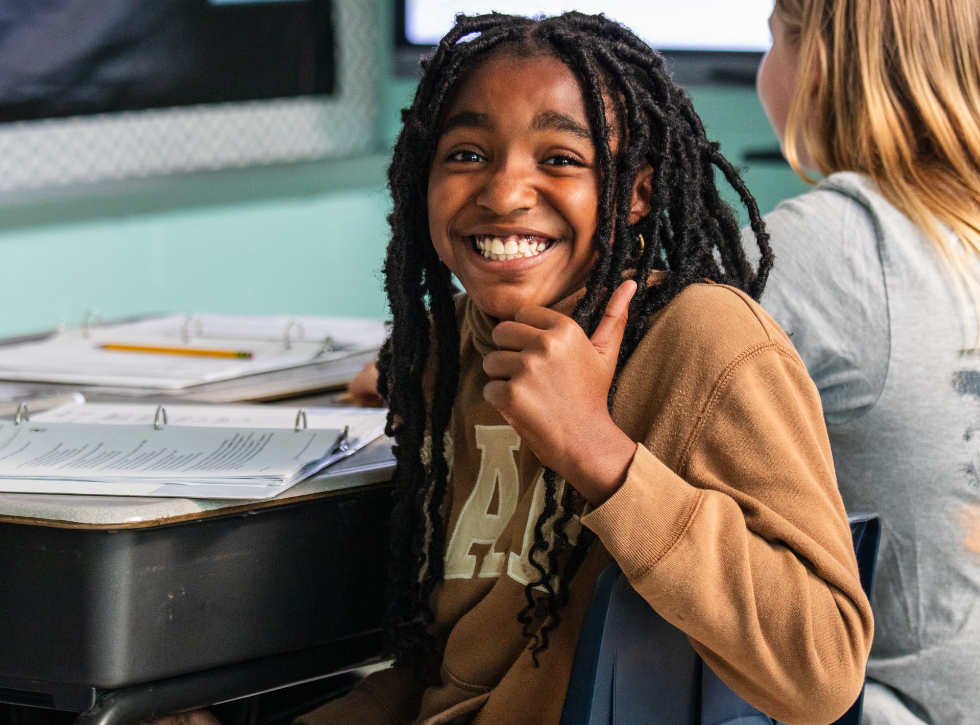 A middle school student in a CommonLit 360 classroom smiling.