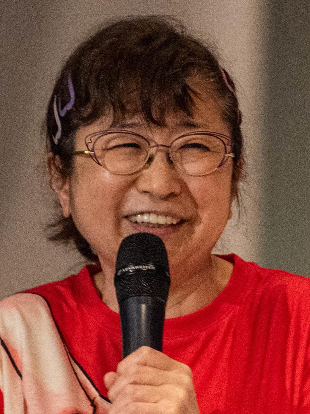 Japanese voice actor Mayumi Tanaka laughing onstage during a panel at Yokota-Con in 2023.