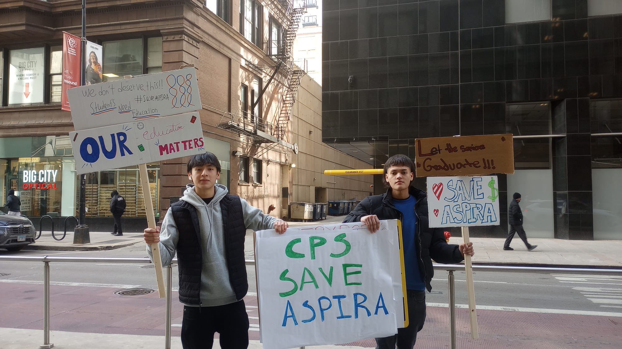 Two teenage boys hold signs reading, "Save ASPIRA."