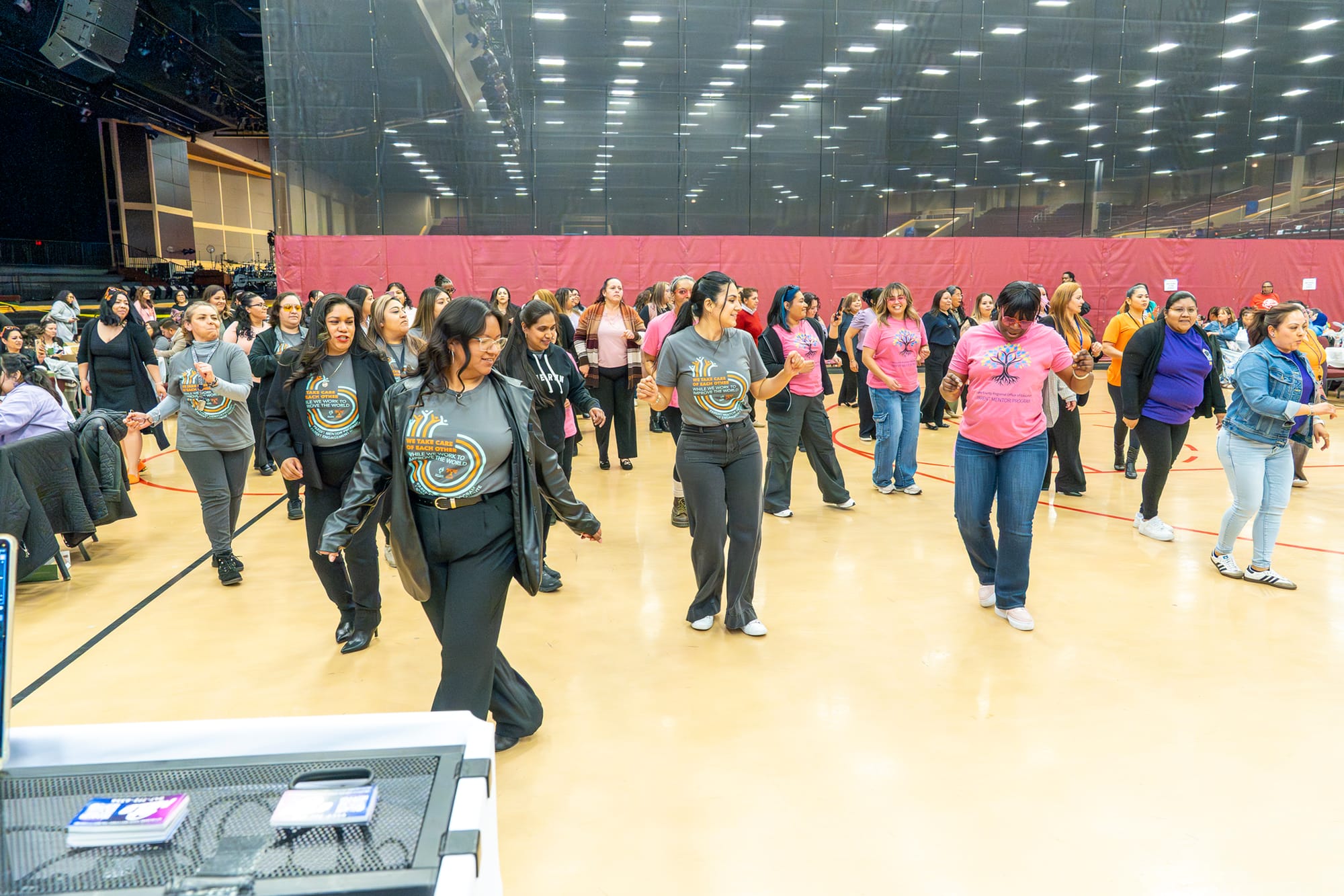 The photo shows about 30 women line dancing on a basketball gym floor.