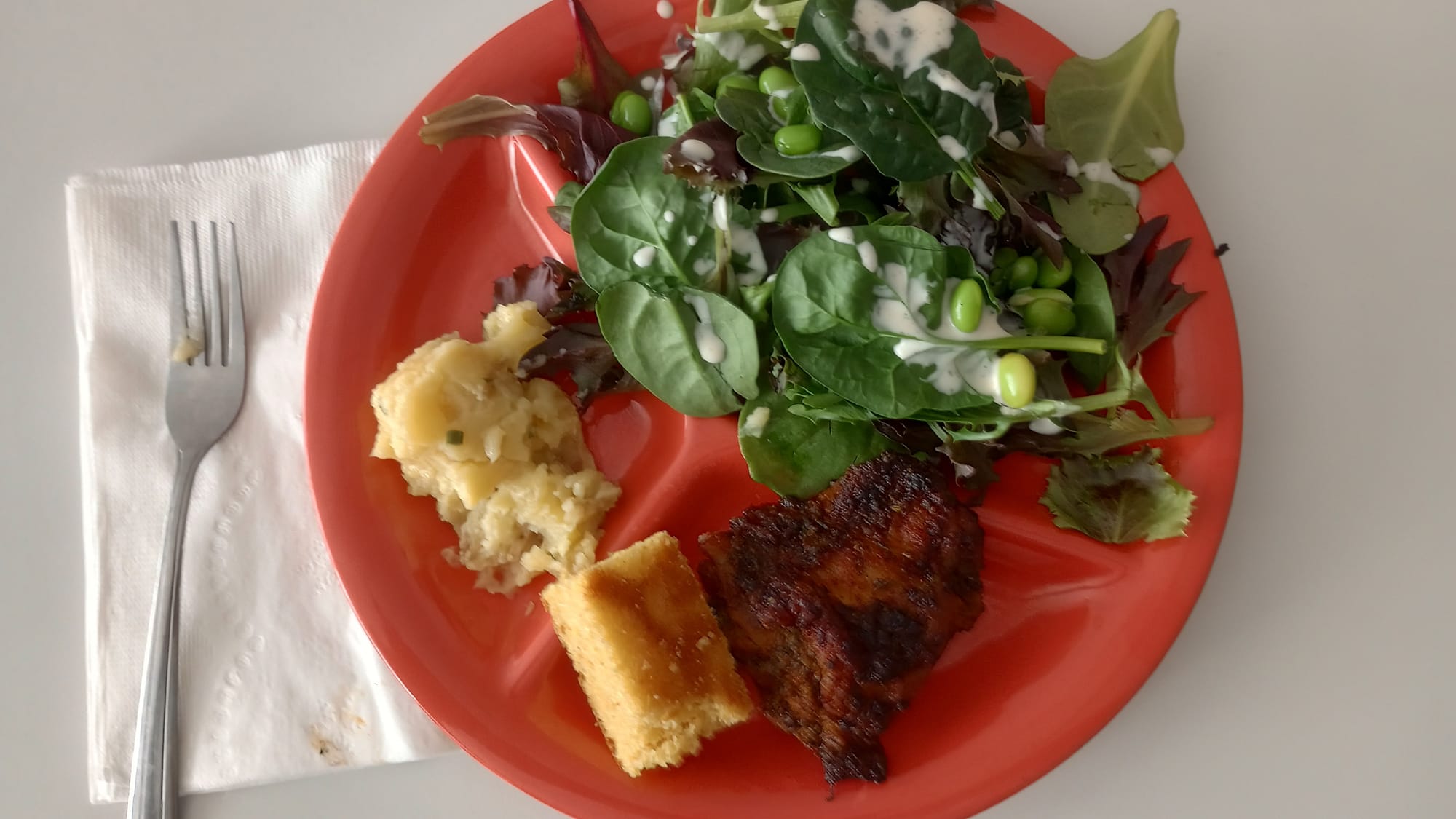 The image shows a plate with salad, baked chicken, cornbread and mashed potatoes.