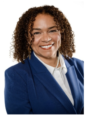 The image shows a Black woman in a navy blazer, white shirt, and pearls.