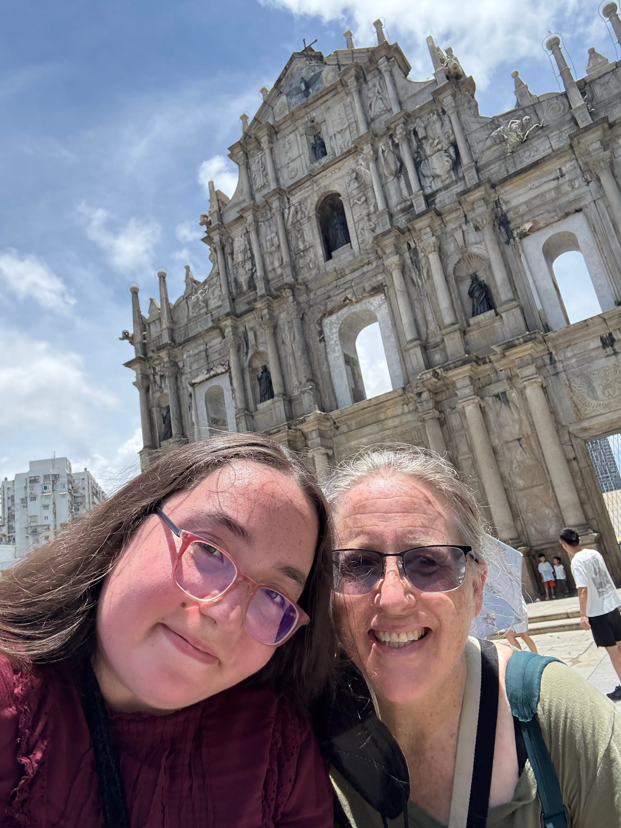 Two women pose in front of a giant Catholic church facade.