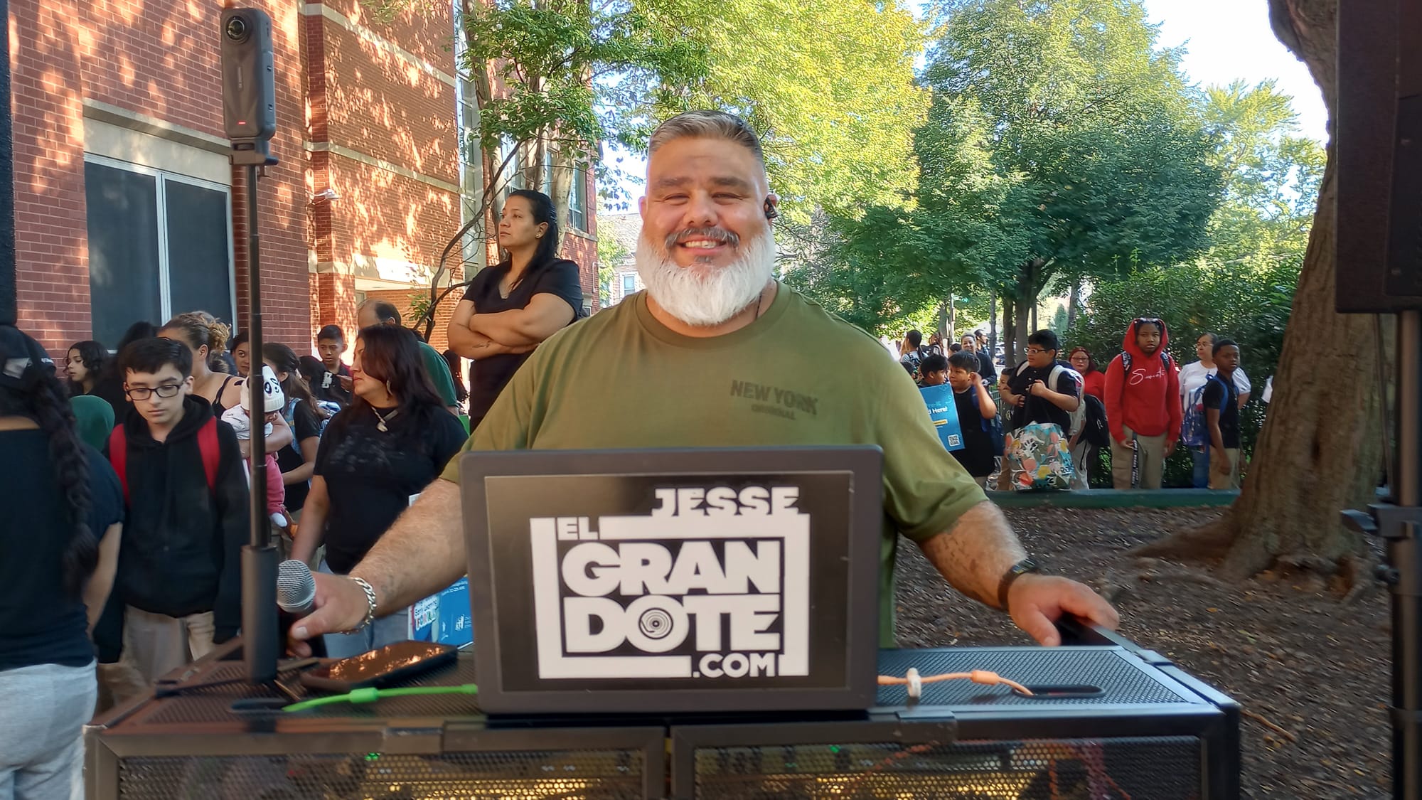 A big man with a full white beard DJs and smiles over his sound system. 