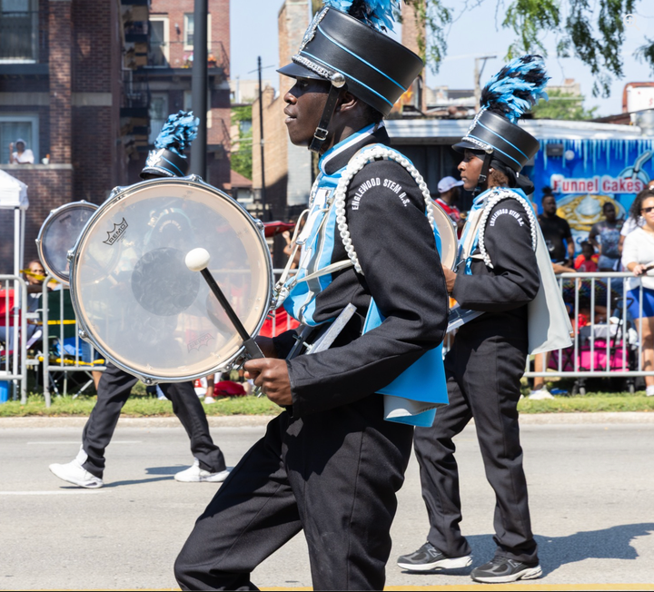 A teenage boy marches with a bass drum in the Bud Billiken Parade.