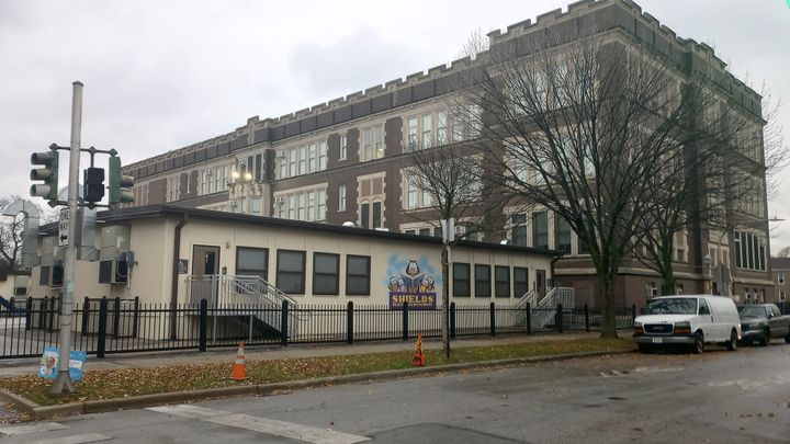 The photos shows the massive main building of Shields Elementary in the background, two modular classroom units in the foreground.
