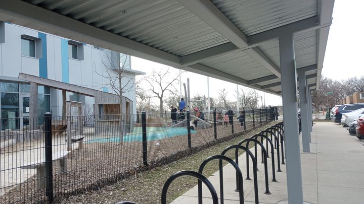 Children play at recess. A modern, eco-friendly school buidling and a set of bike racks are also visible.
