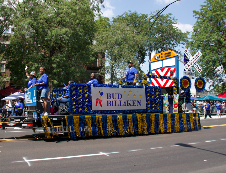 The image shows a blue and gold float with a "Bud Billiken" sign.