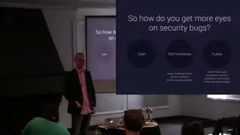 Casey Ellis on stage at SOURCE Boston 2014, next to a slide asking "So how do you get more eyes on security bugs?"