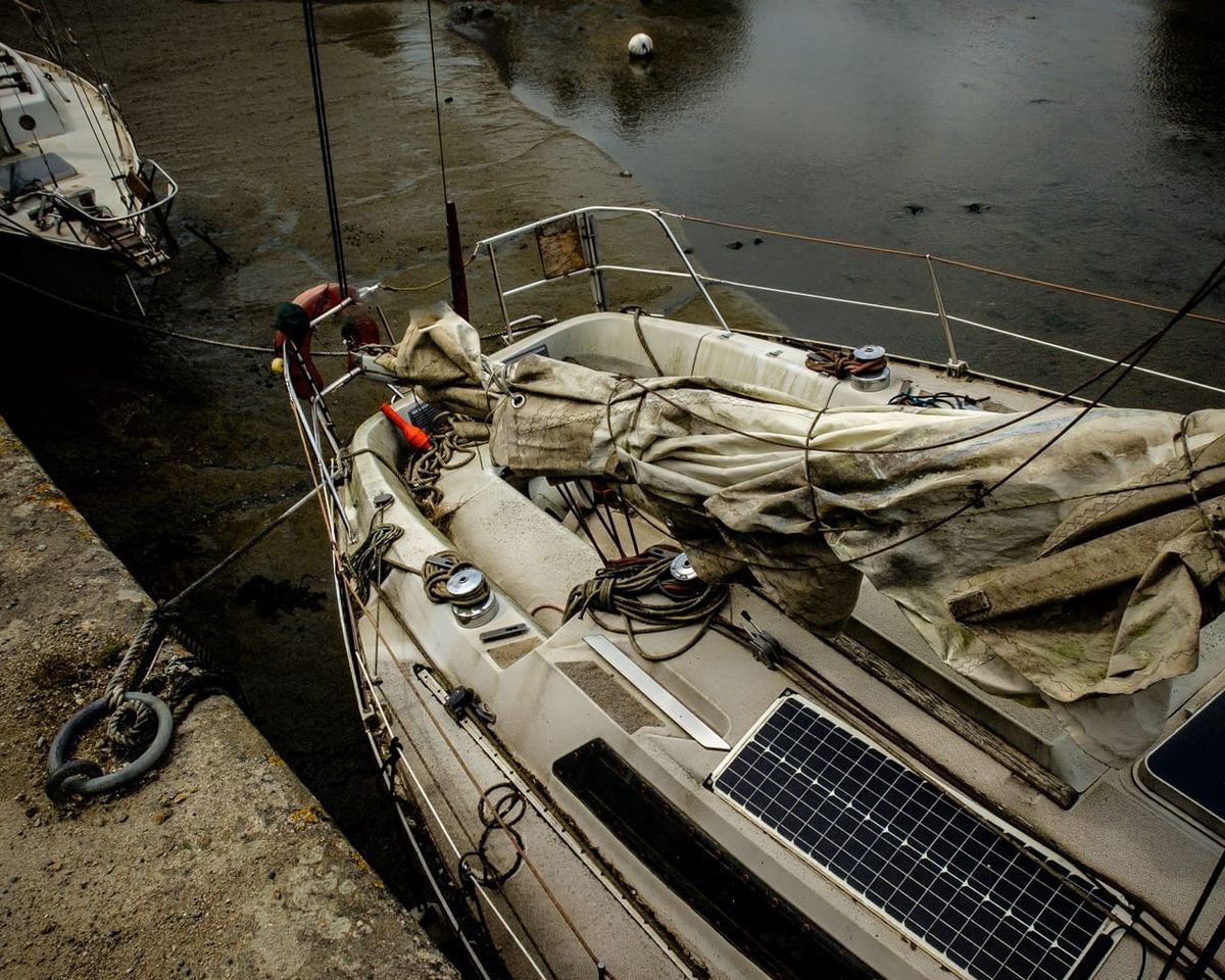 Voilier abandonné à marée basse dans le port de Pont-l'Abbé, Finistère, sous une lumière hivernale