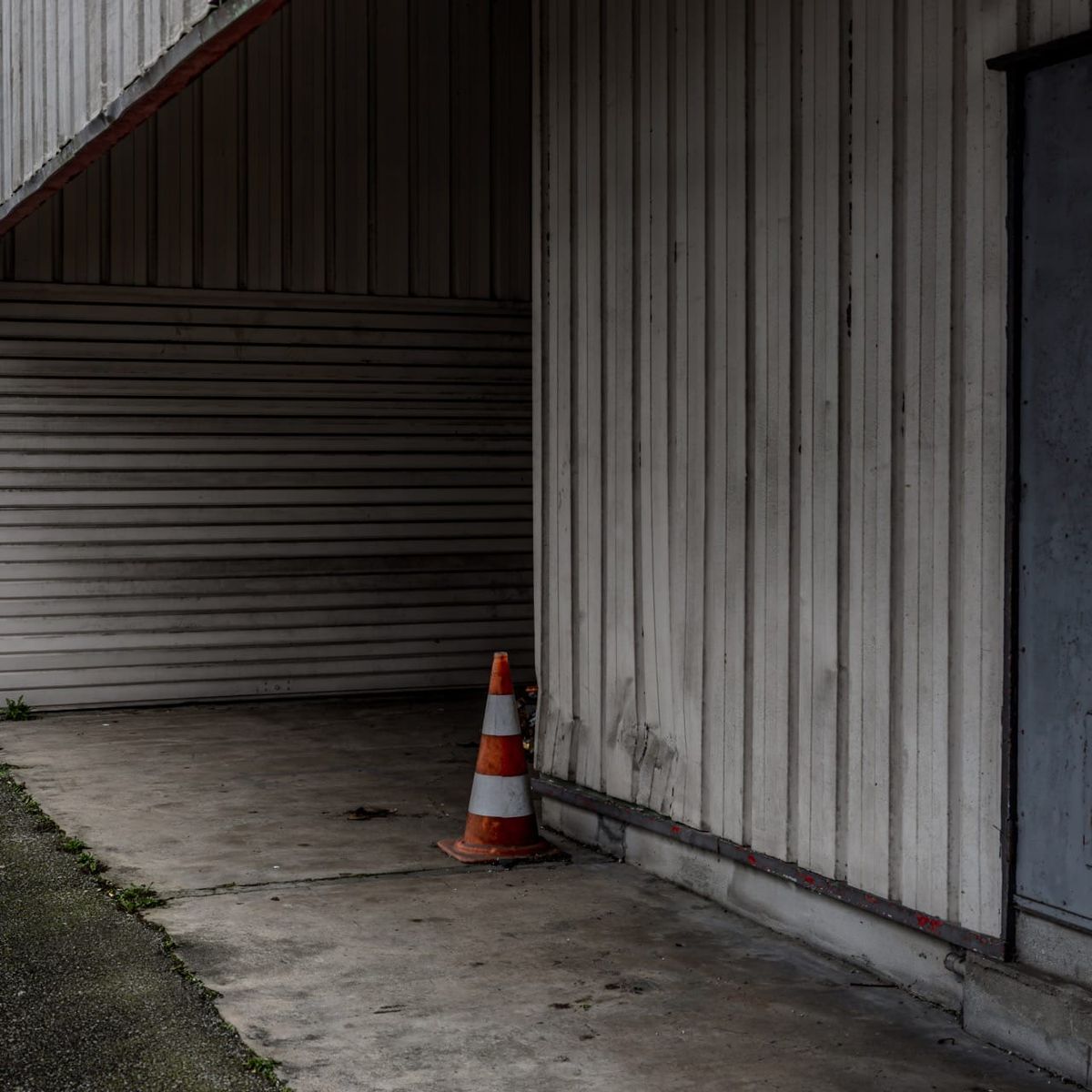 Rideau métallique strié et cône de chantier solitaire dans une zone industrielle de Quimper, 1er janvier