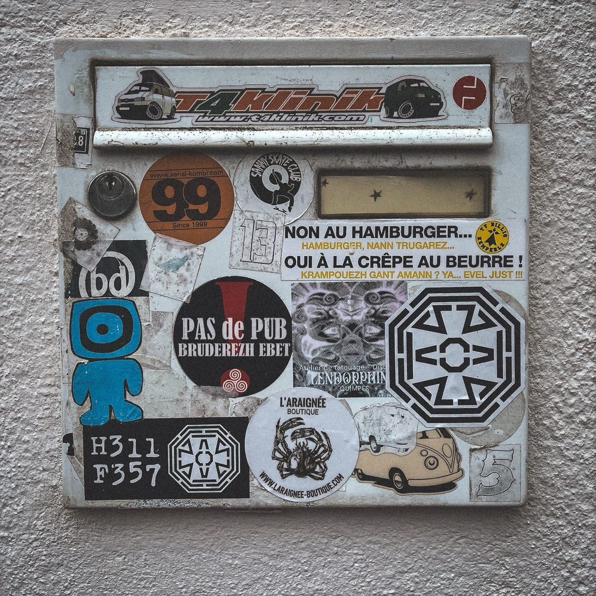 Boîte aux lettres murale couverte d’autocollants culturels et bretons, quartier de Quimper.