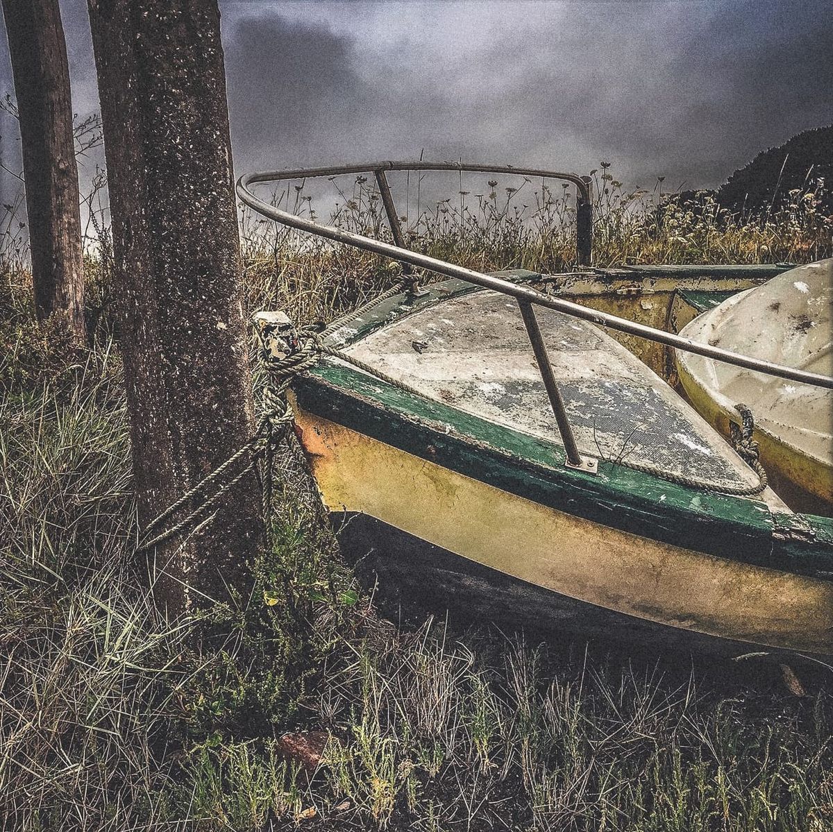 Barque attachée à un poteau, posée dans l’herbe sèche, sans eau autour, à Crozon